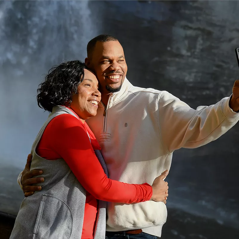 Couple taking a selfie in front of a waterfall.