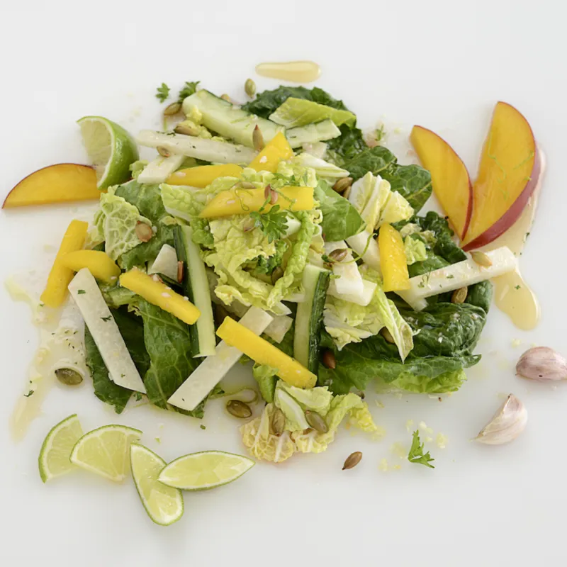 Mound of jicama, cabbage, and mango salad on white surface.