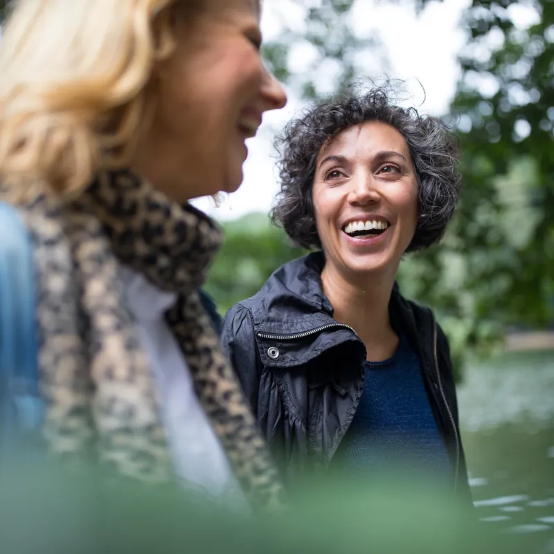 Two smiling women walking outdoors.