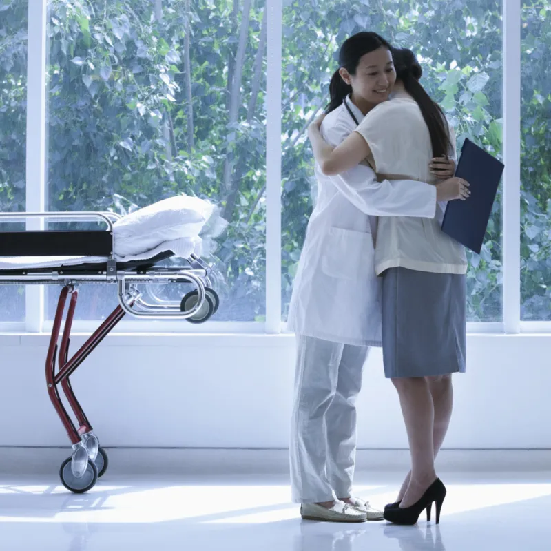 Doctor hugging a transplant patient in a large hallway, near a gurney.