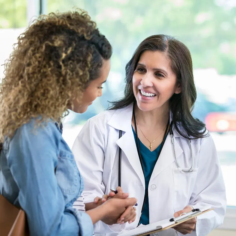 Doctor holding a clipboard and holding hands with a patient