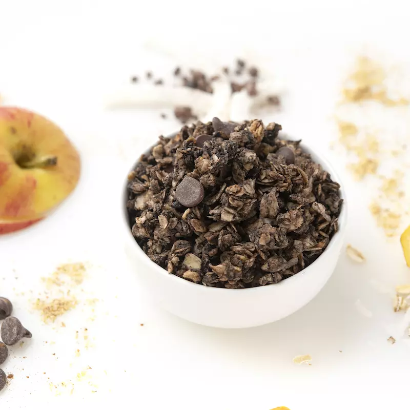 Bowl of chocolate granola with apple garnish on the side