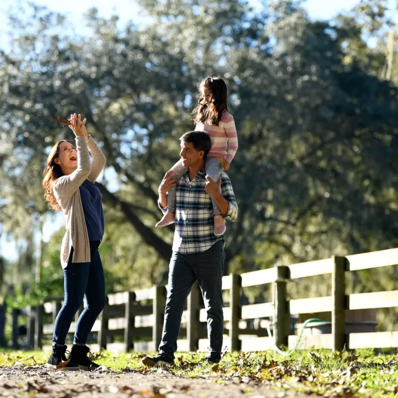 A mother, father, and small daughter walking around a ranch