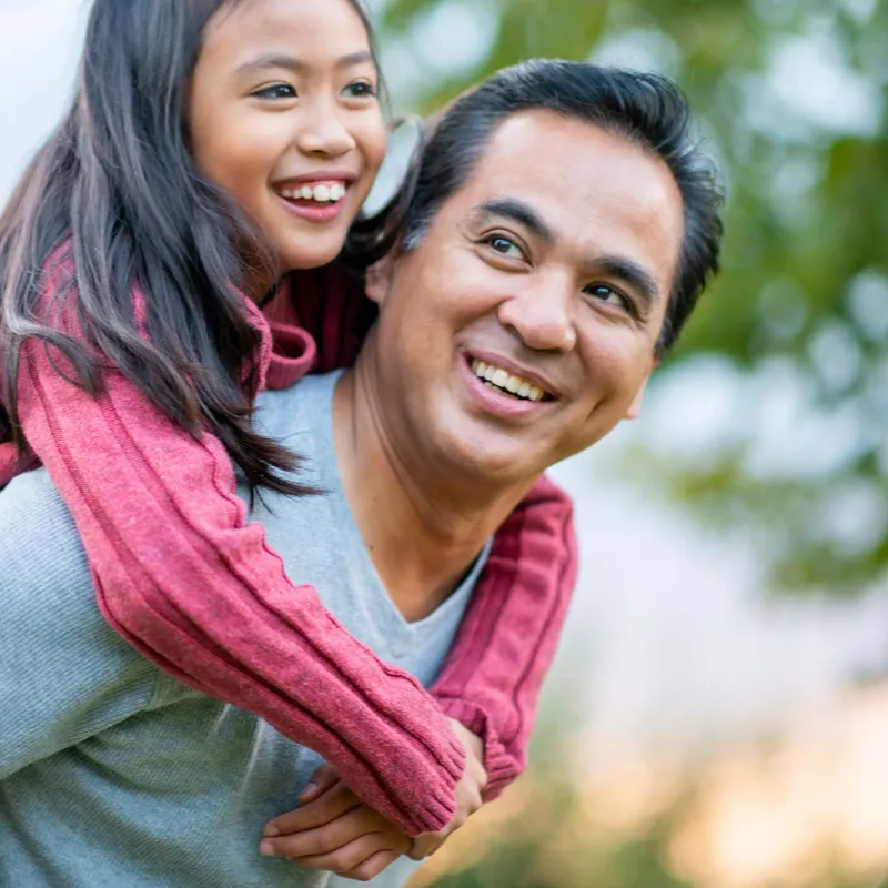 A father giving his young daughter a piggyback ride