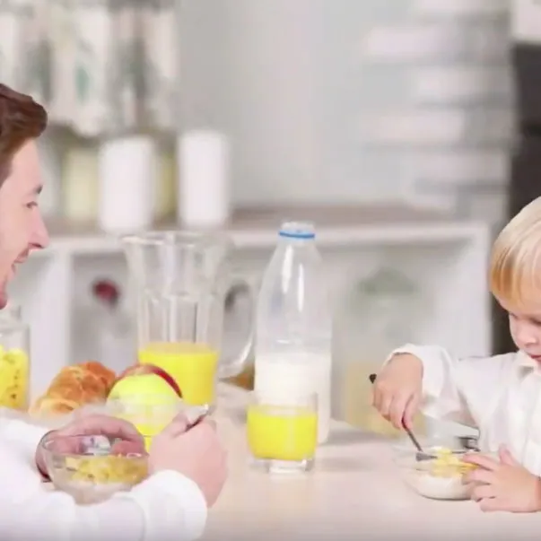 Father and young song eating breakfast at a table together.