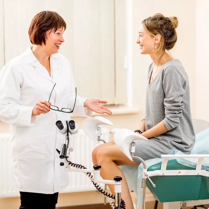 A female doctor talks with a patient in a hospital room.