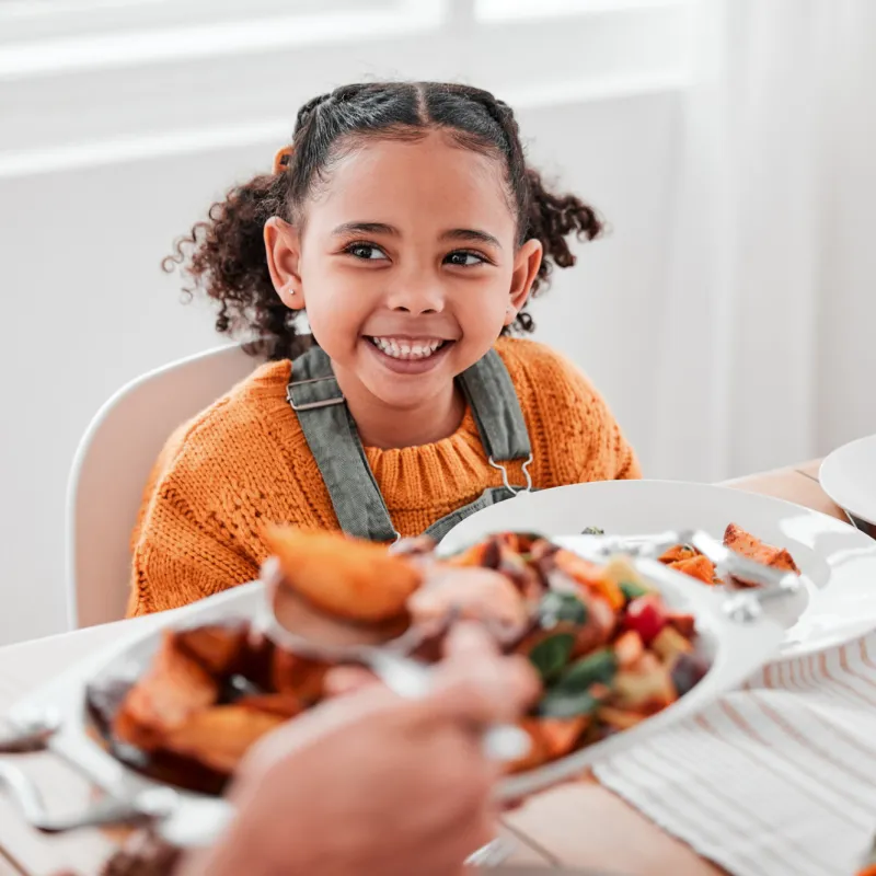 A girl smiling at the dinner table.