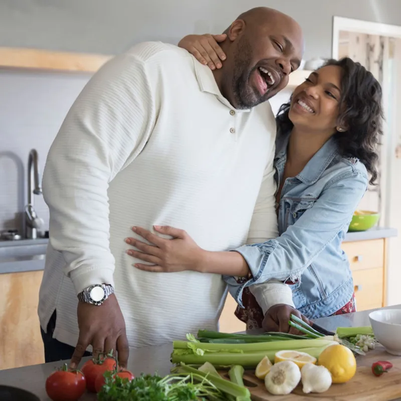 A couple hugging each other while cooking on the kitchen