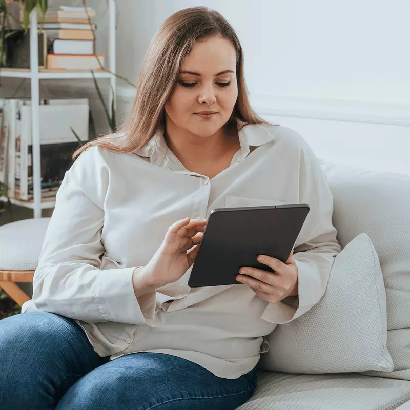 A woman using a tablet on her couch.