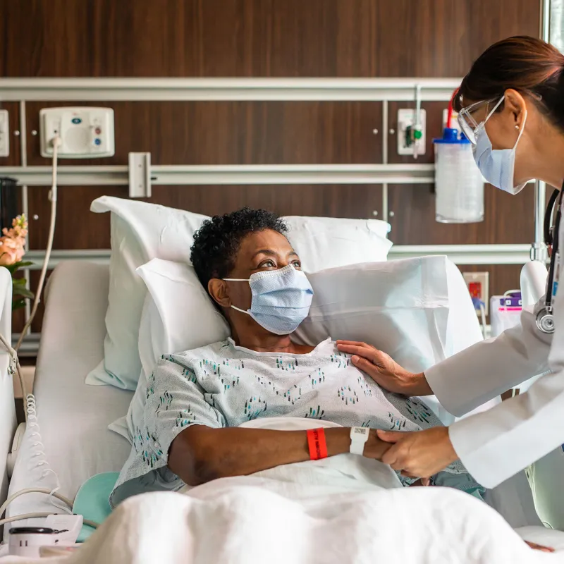 A physician comforting a patient of color