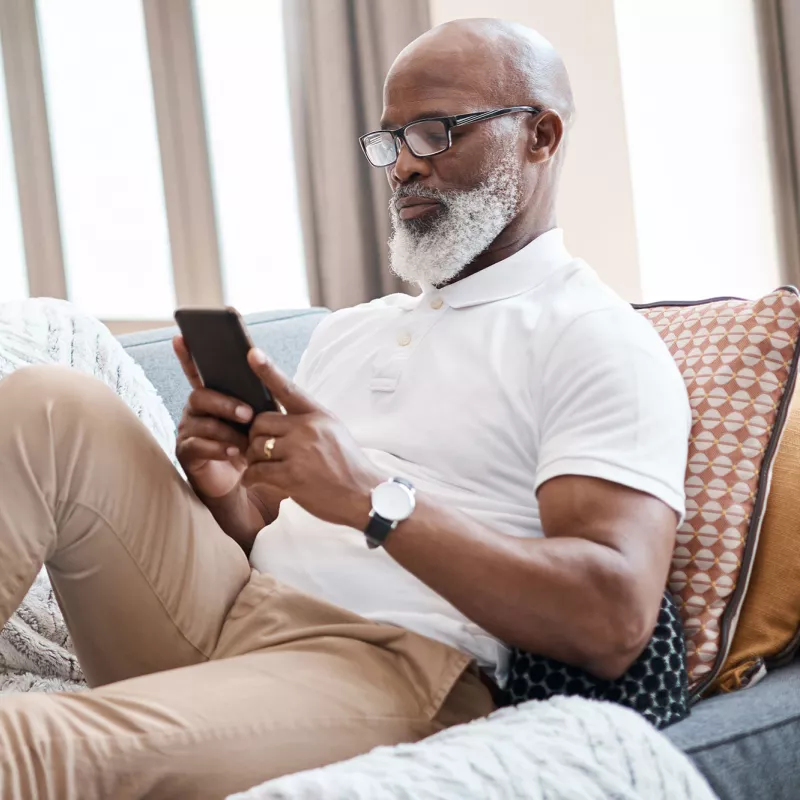 A man checking his phone from the couch. 