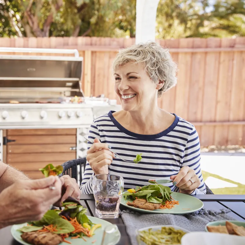 A couple eats a healthy meal together outside.