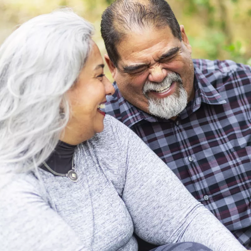 A couple laughs while on an outdoor picnic.