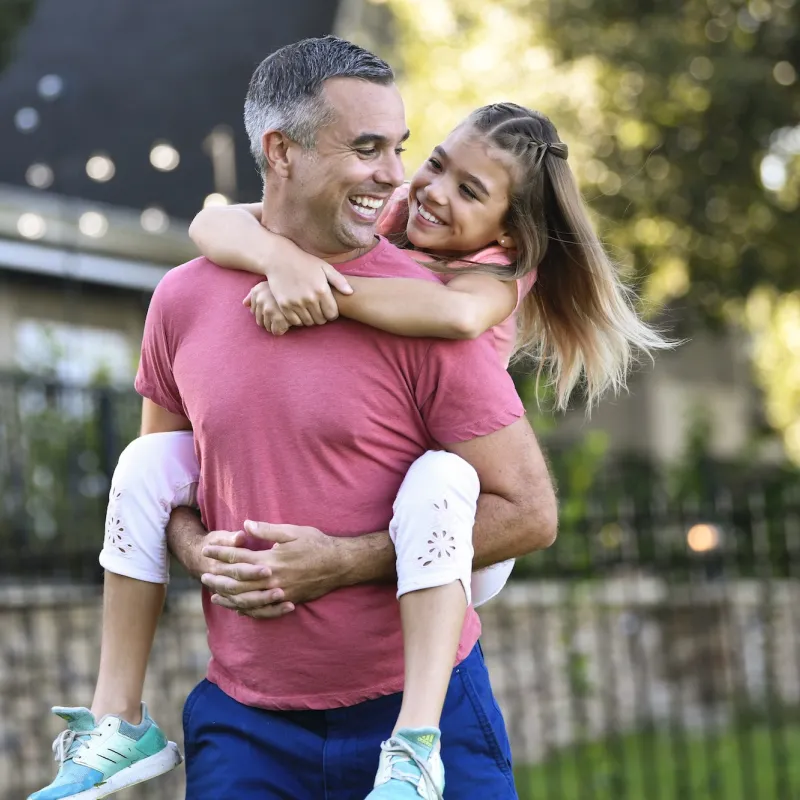 A dad giving his daughter a piggyback ride.