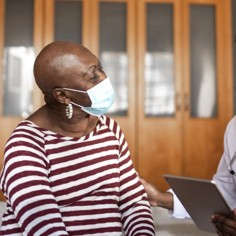 A doctor and patient discuss health care while wearing masks.