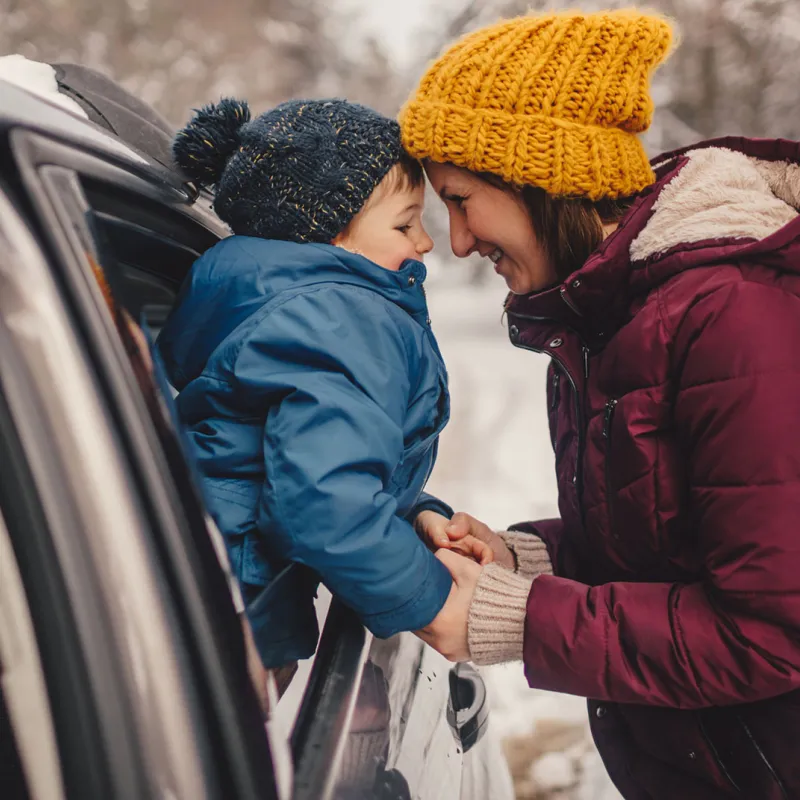 A mom prepares for a road trip with her family in the snow.