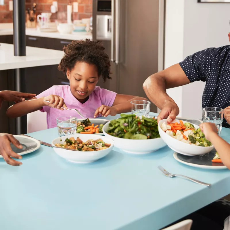 A young family sits down at the table to eat lunch