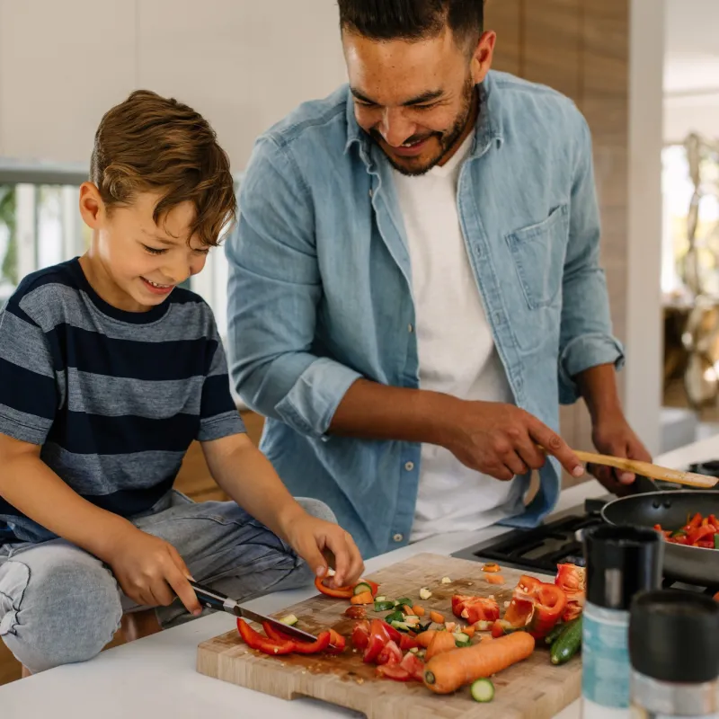 A father and son cook a healthy plant-based meal.