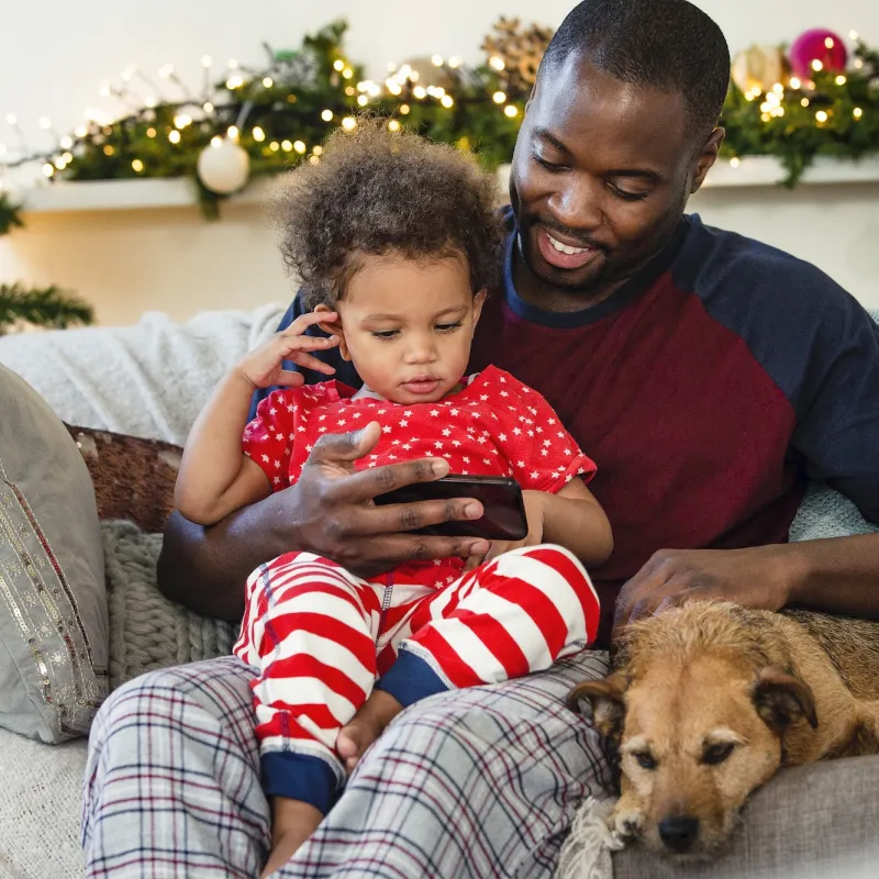 A father an son sit together on the couch during the holiday season. 