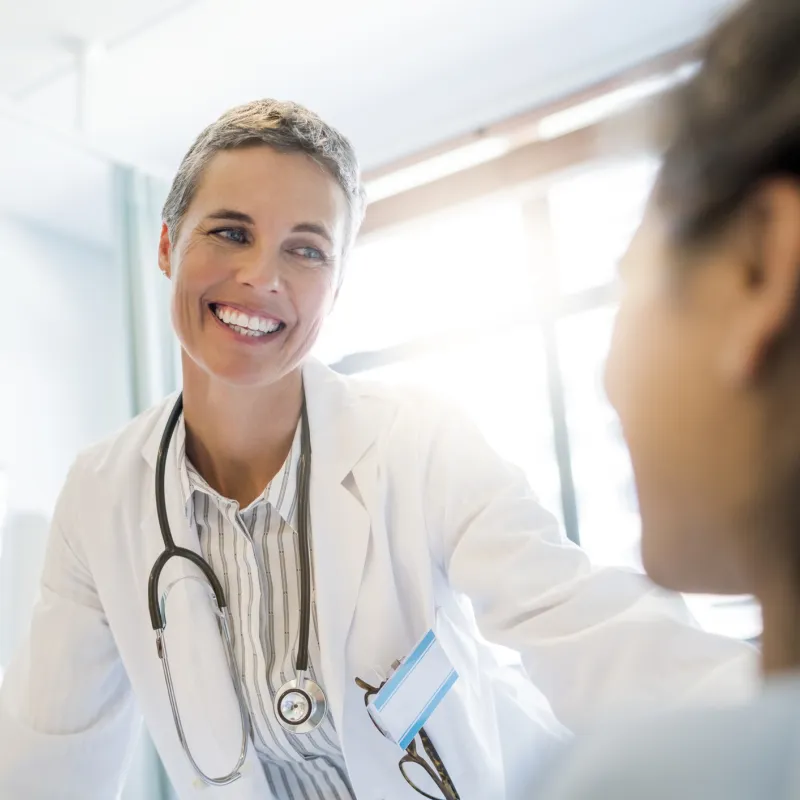 A doctor greets her patient at the bedside