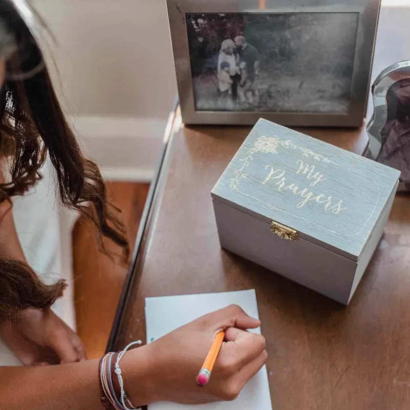 Girl writing prayer with prayer box