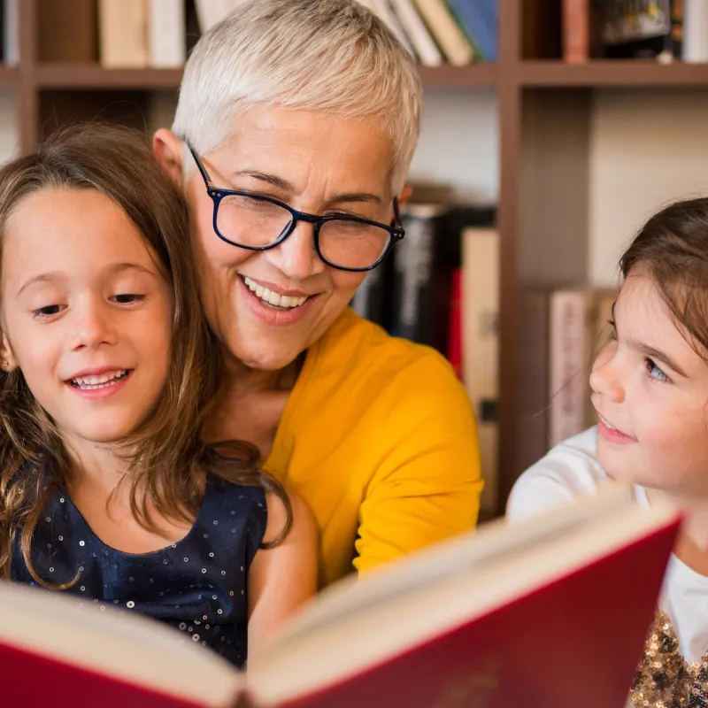 A grandmother reading to her granddaughters. 