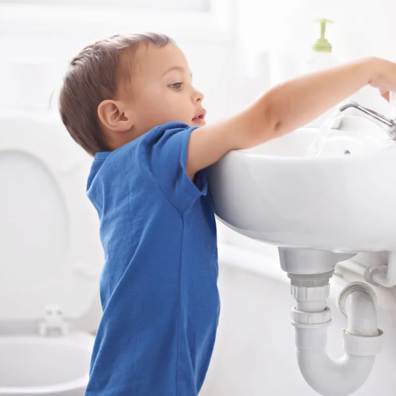 A child turning on the bathroom sink.