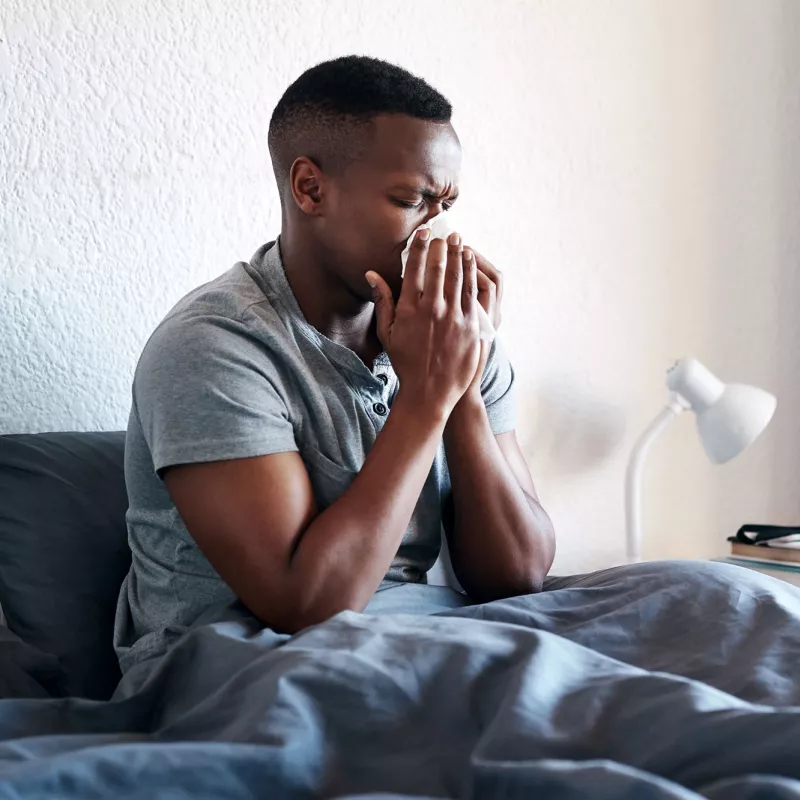 A man blowing his nose at home.