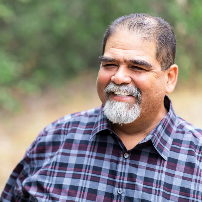 A mature man smiling and outdoors