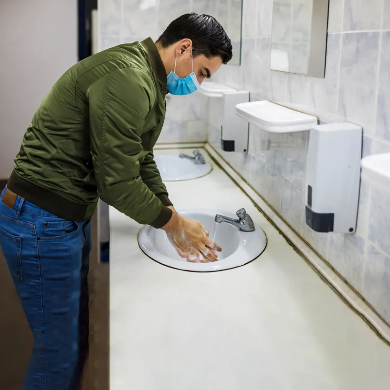 A man washing his hands in a public restroom.