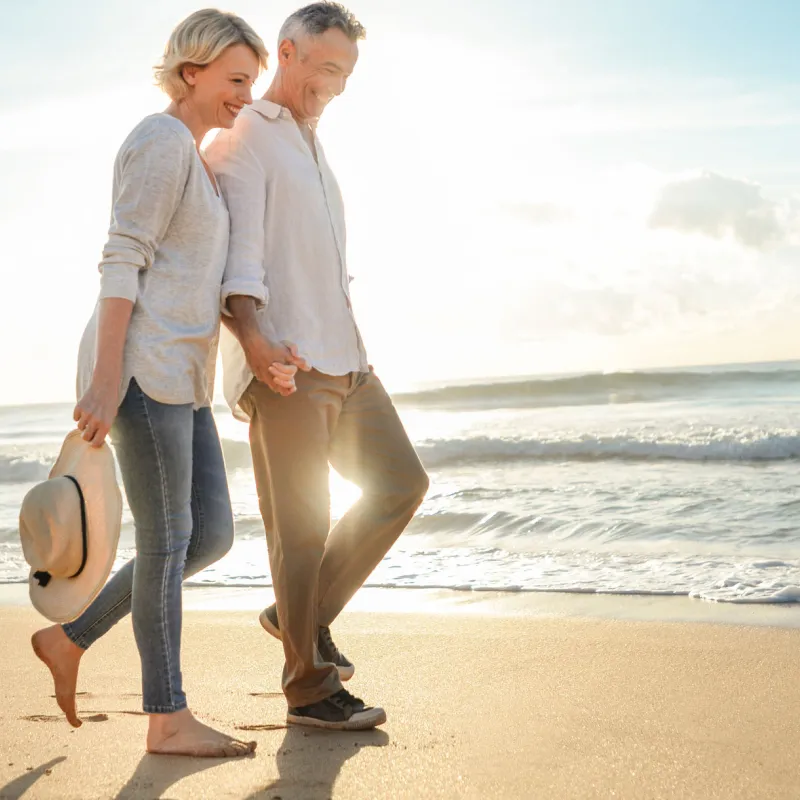 A couple walks on the beach near sunset.