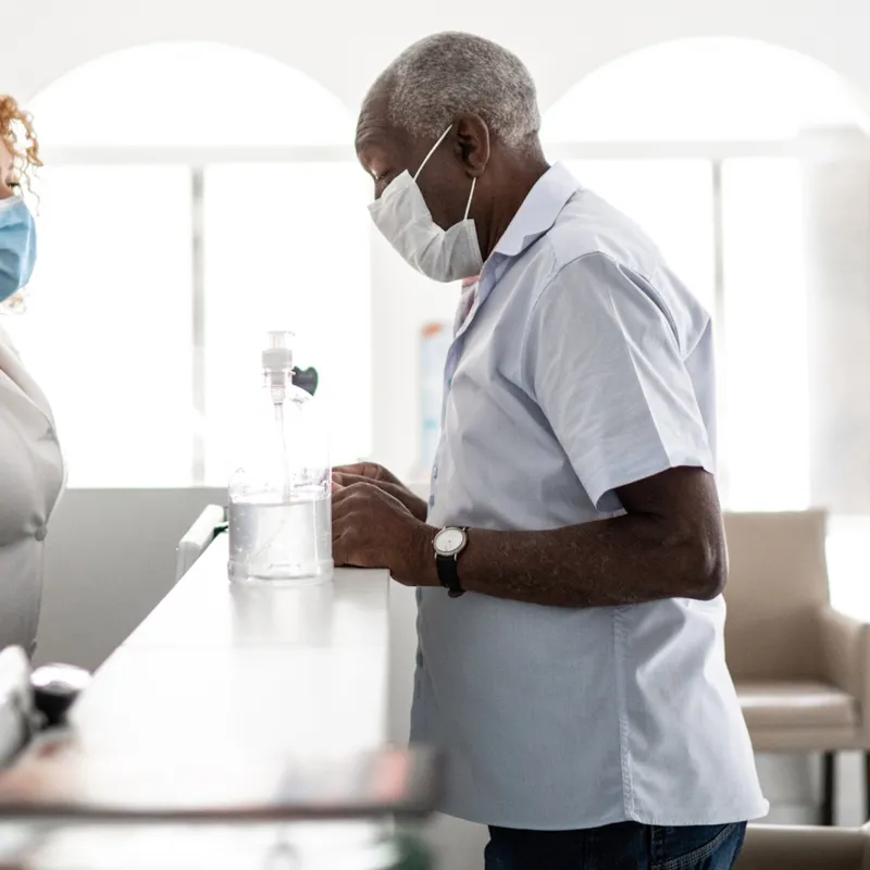 A man wearing a mask checking in for an appointment.