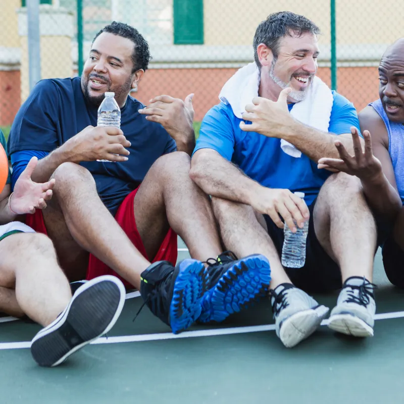 A group of men resting on the sidelines during a game of basketball.