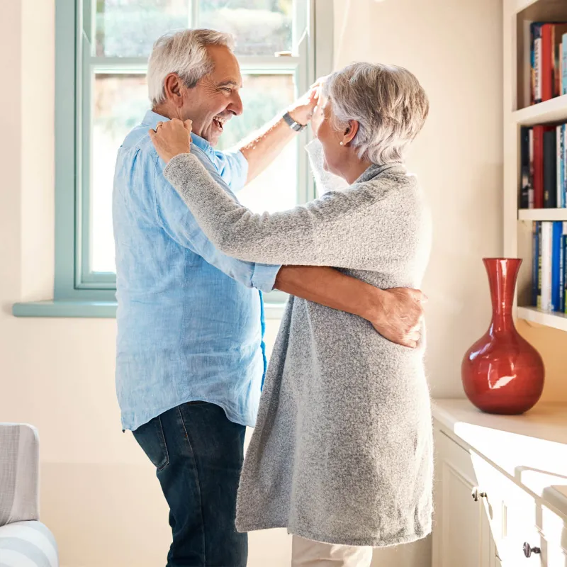 A mature couple dancing at home.