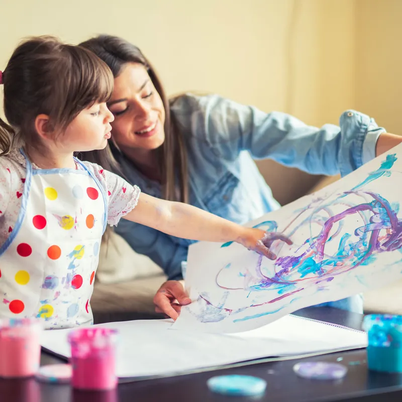 A mother and young daughter painting together. 