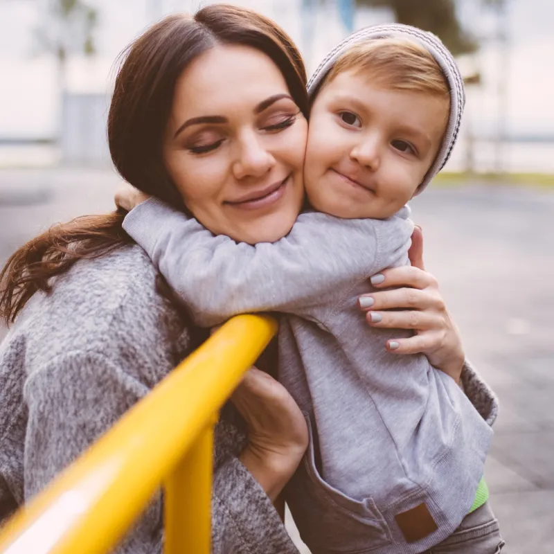 A mom hugs her son at the playground.