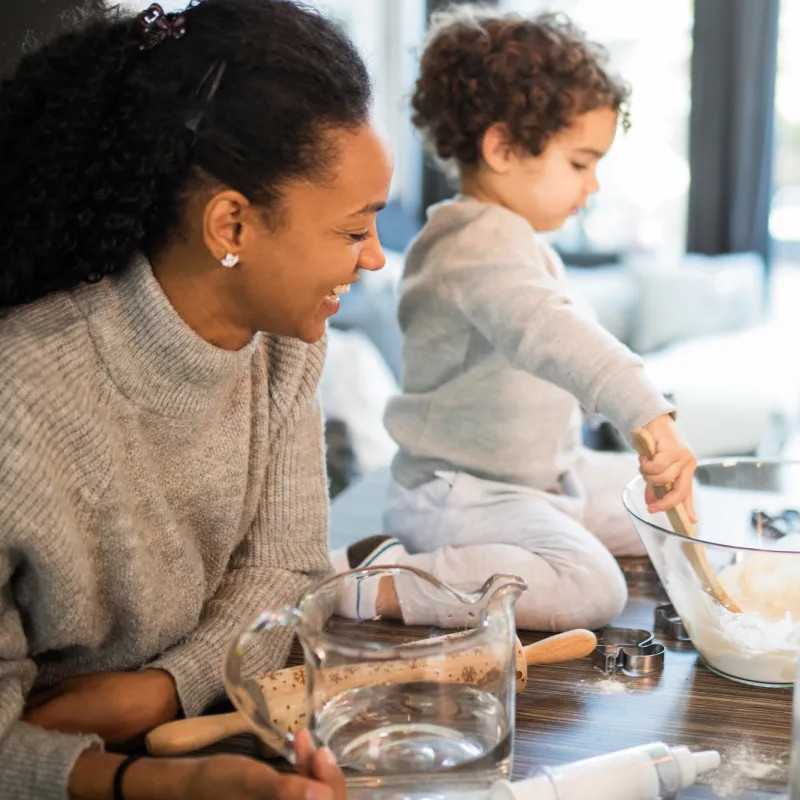 A mom and her toddler bake Christmas cookies together.