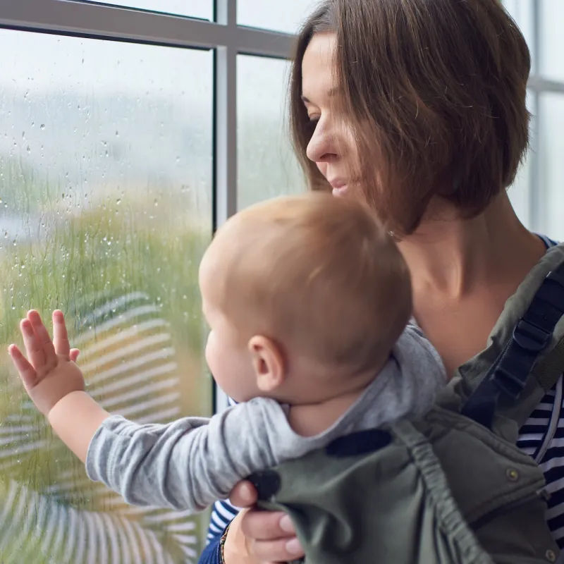 A mom keeps her baby safe indoors during a rain storm.