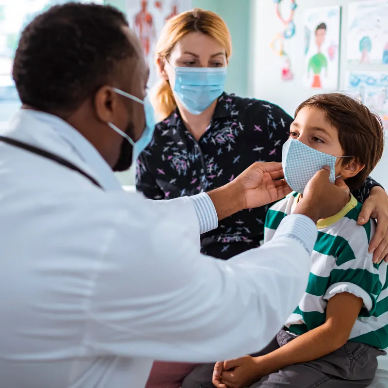 Mother and son at a doctor's office while wearing masks.