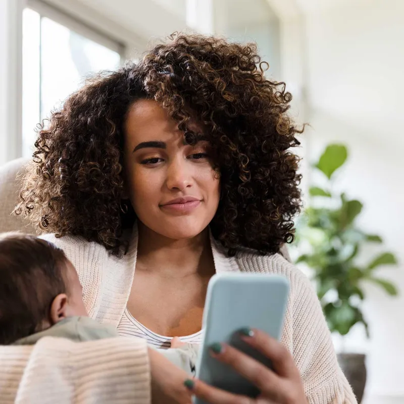 Mother holding baby while on a cell phone