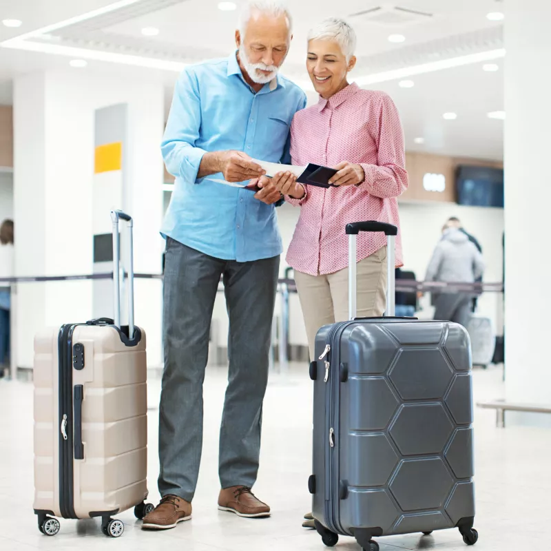 An older adult couple prepares to take a flight at the airport.