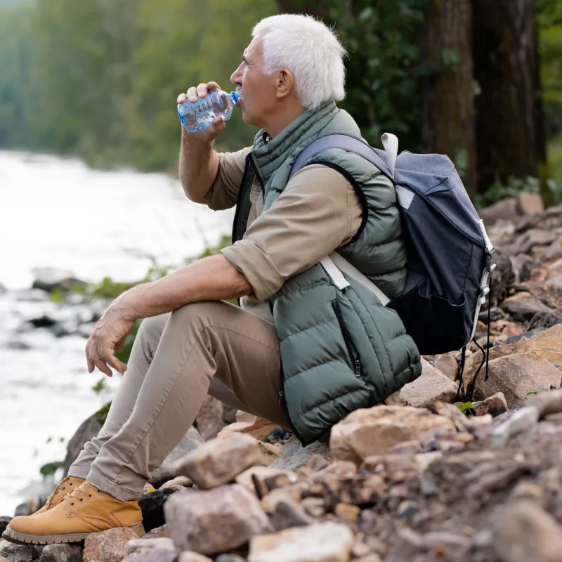 A man taking a water break on a hike.