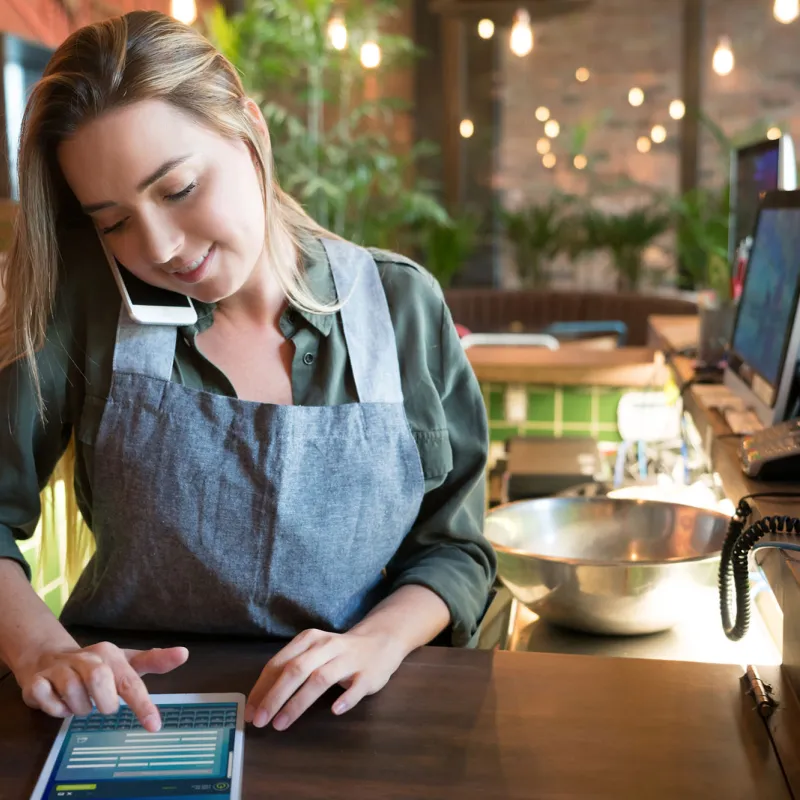 A young waitress taking a to-go order over the phone.