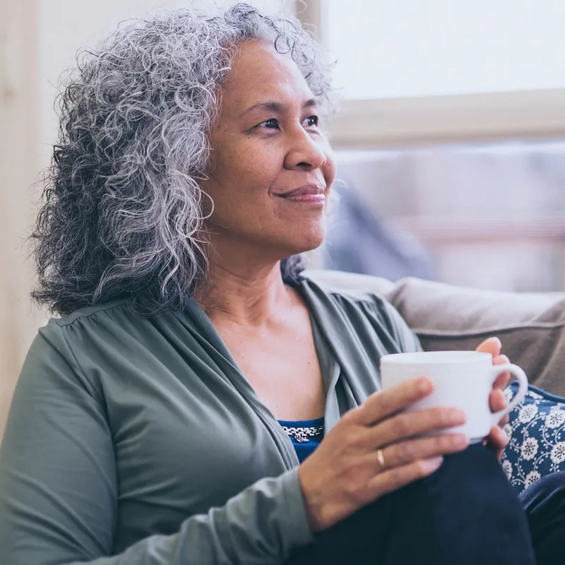 A woman sits by the window drinking tea.