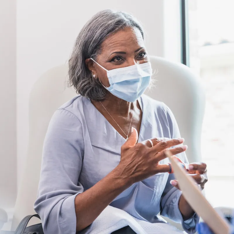 A mature woman visiting her doctor while wearing a mask.