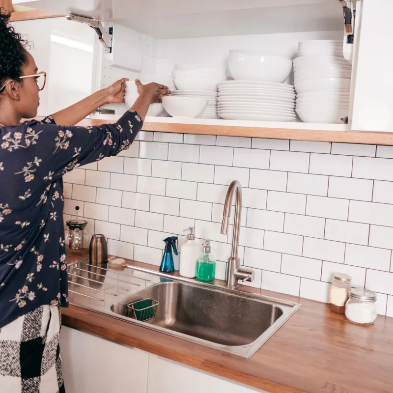 A young adult woman organizing items in her kitchen