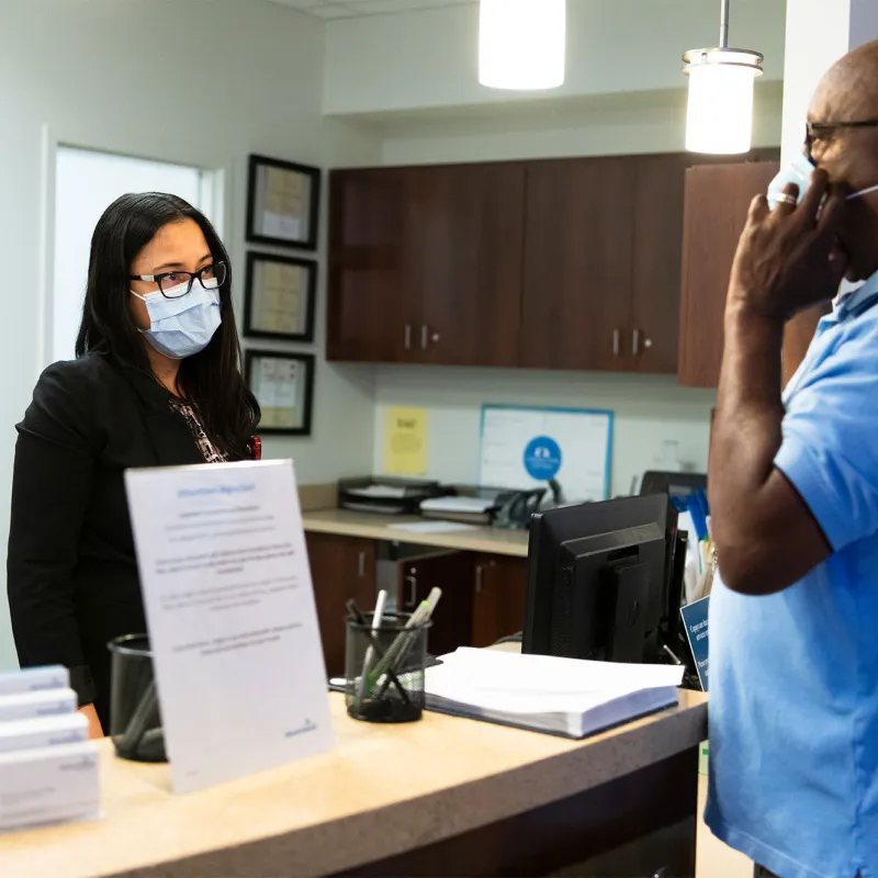 A patient checking in for an appointment and wearing a mask.