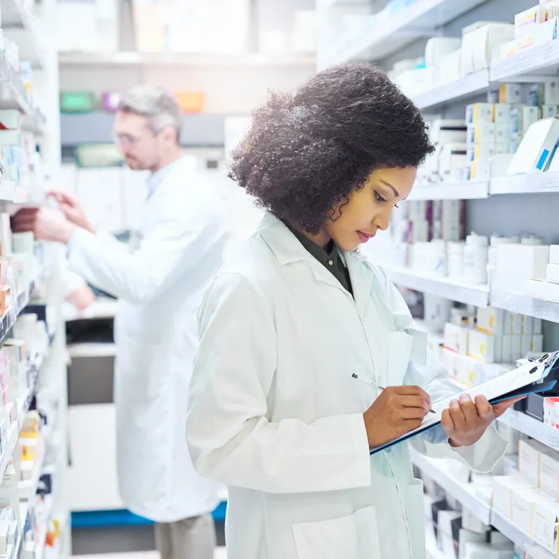 Female and male pharmacist working in an aisle in a pharmacy.