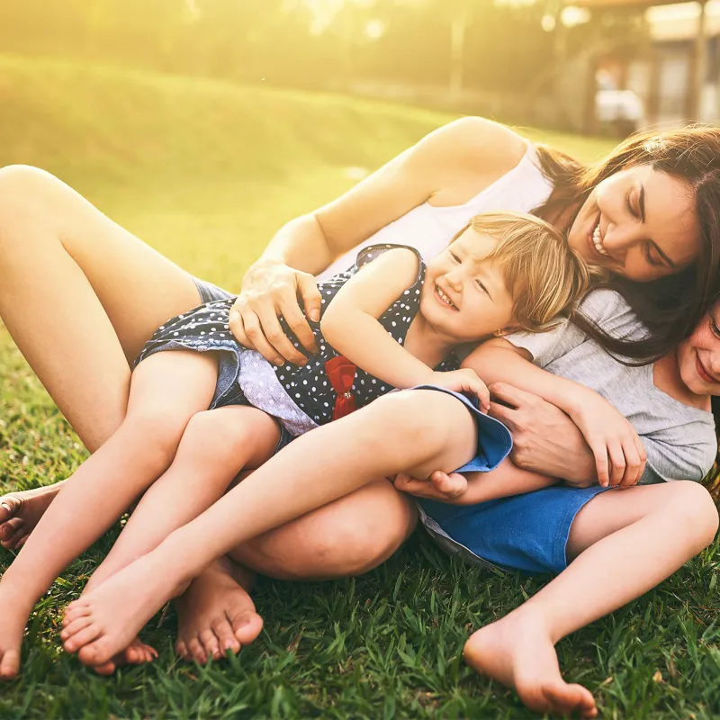 Mother playing with her children on the lawn.