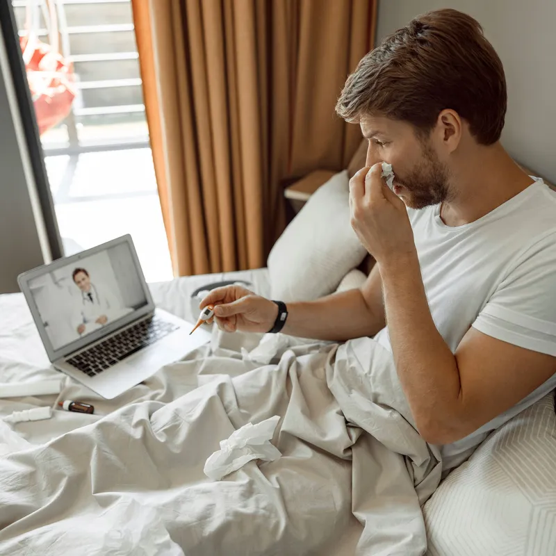 A young man has a remote check up with his doctor from home